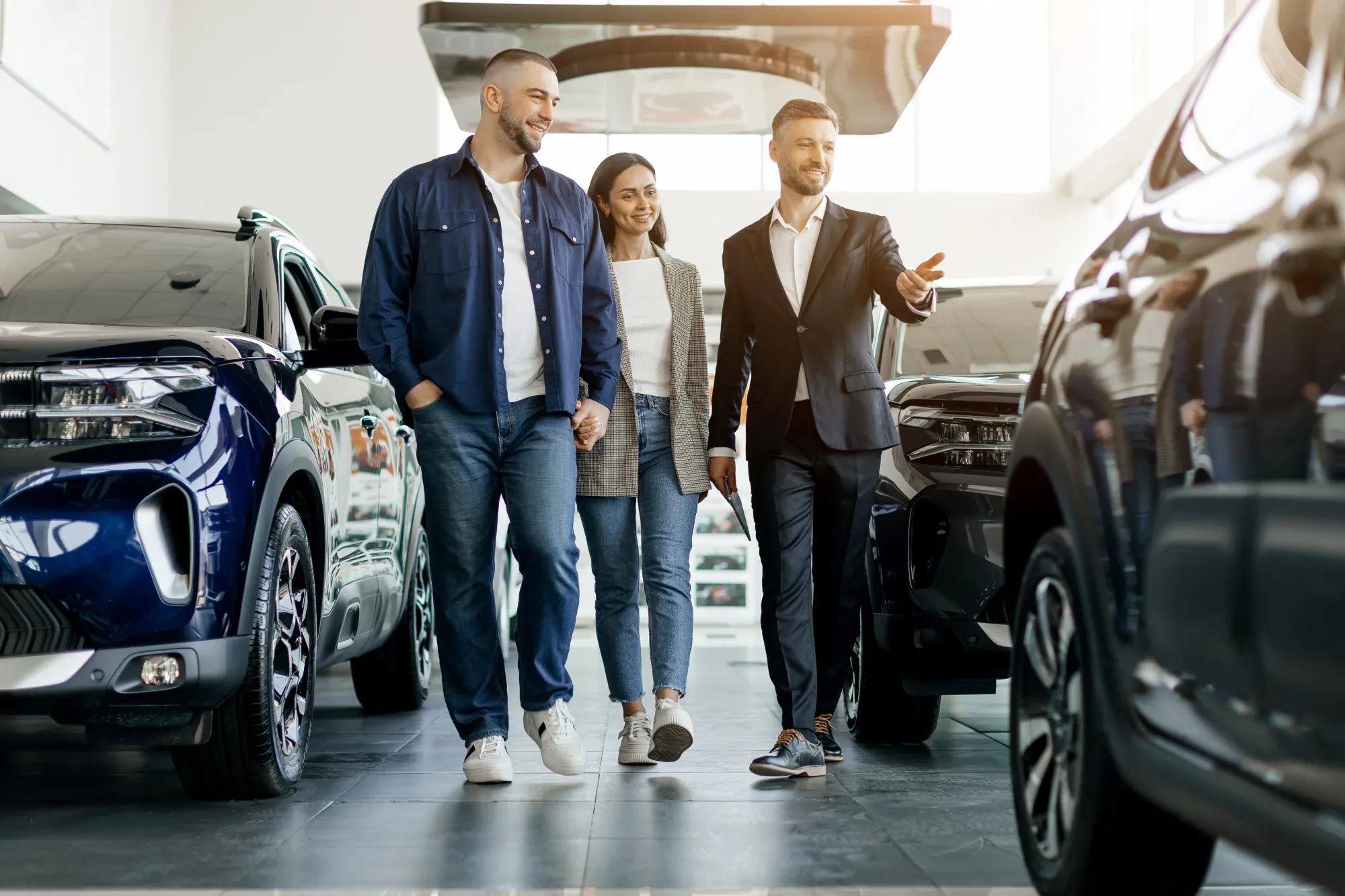 A salesperson walking a couple through a bright dealership showroom